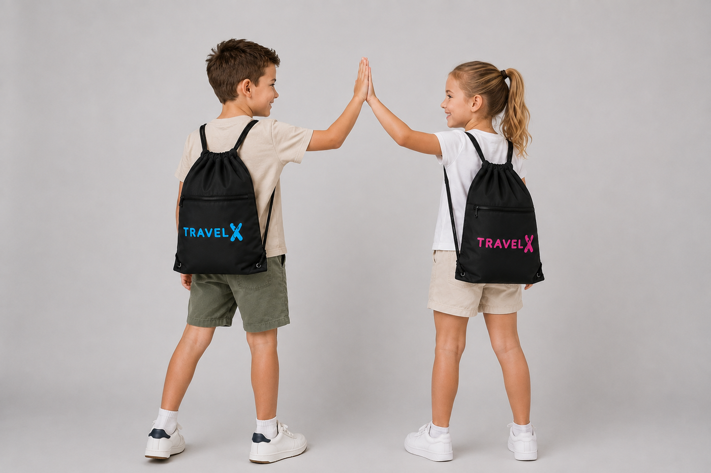 Boy and girl wearing Travel X Go Bags in blue and pink, high-fiving