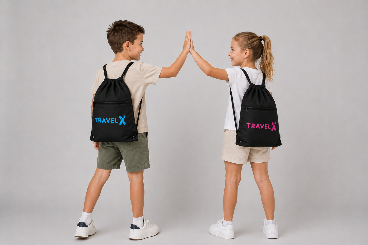 Boy and girl wearing Travel X Go Bags in blue and pink, high-fiving